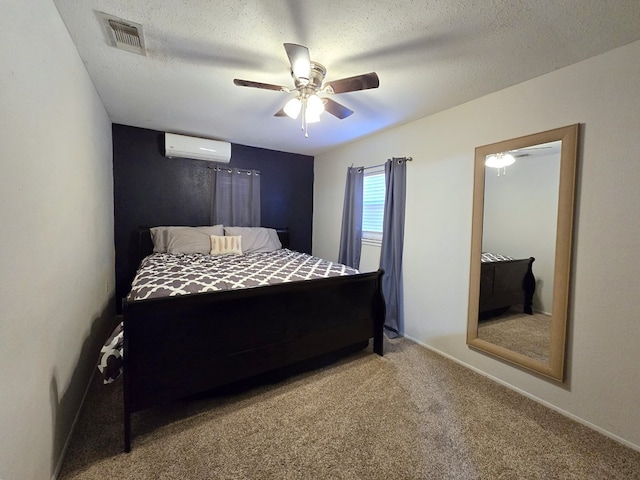 bedroom with ceiling fan, carpet floors, a textured ceiling, and a wall unit AC