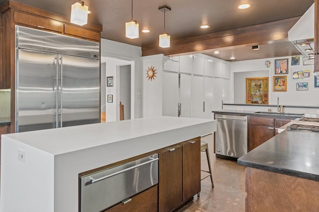 kitchen with appliances with stainless steel finishes, a breakfast bar, decorative light fixtures, sink, and a large island