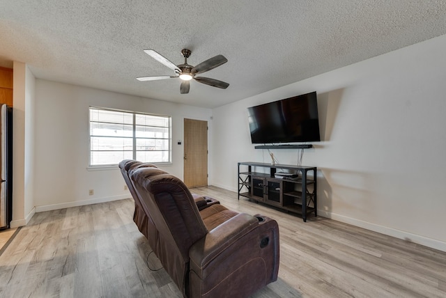 living room with ceiling fan, a textured ceiling, and light hardwood / wood-style floors