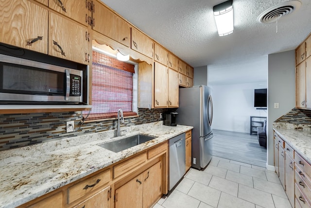 kitchen featuring light stone countertops, sink, backsplash, and appliances with stainless steel finishes