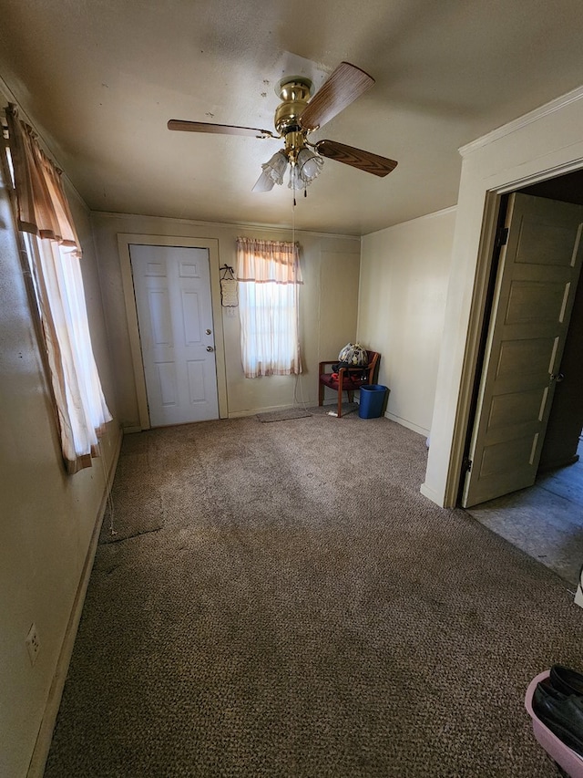 foyer featuring ornamental molding, carpet flooring, a ceiling fan, and baseboards