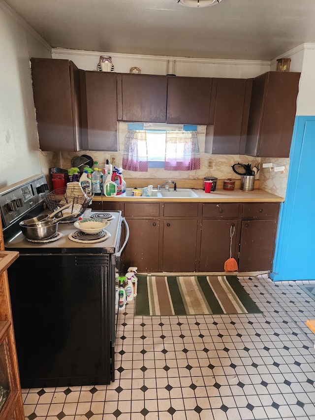 kitchen with light countertops, crown molding, electric range, and light floors