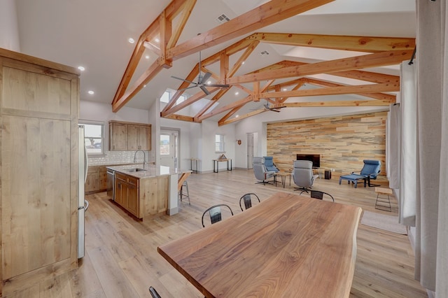 dining room featuring beam ceiling, sink, high vaulted ceiling, and light wood-type flooring