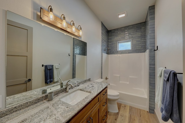 full bathroom featuring hardwood / wood-style floors, vanity, toilet, and tiled shower / bath