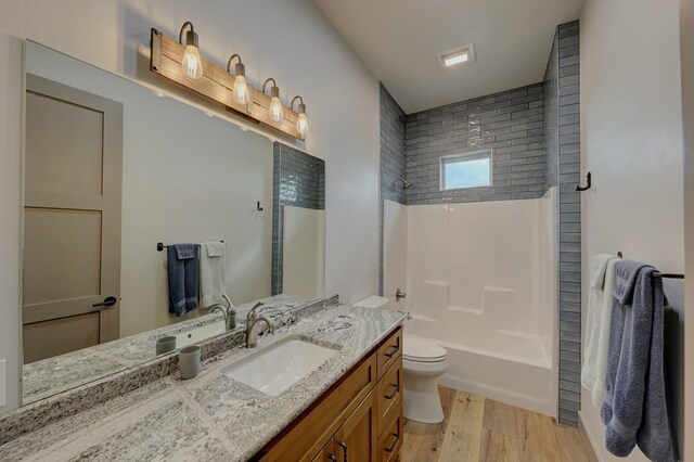 full bathroom with hardwood / wood-style floors, vanity, toilet, and tiled shower / bath