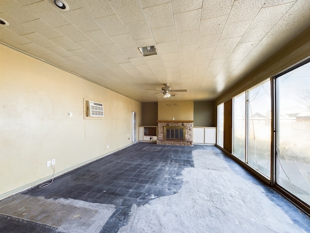 unfurnished living room with ceiling fan, a fireplace, and an AC wall unit