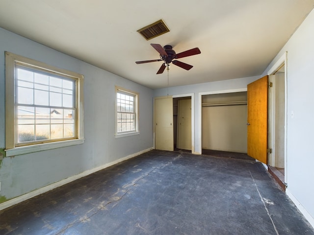 unfurnished bedroom with two closets and ceiling fan