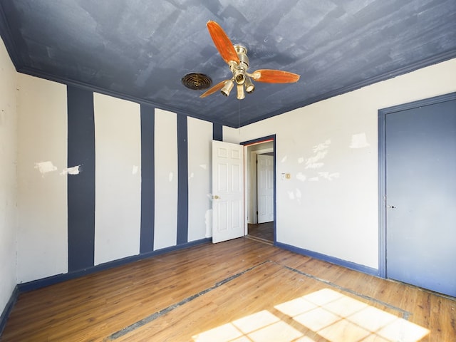 unfurnished bedroom featuring wood-type flooring, ornamental molding, and ceiling fan