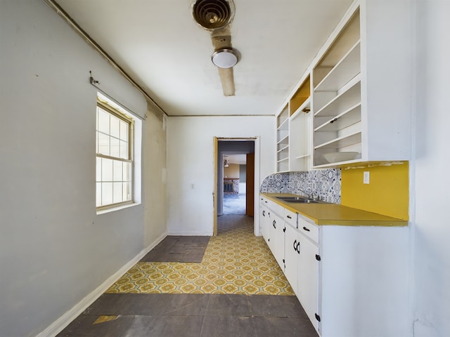 kitchen with tasteful backsplash, sink, and white cabinets