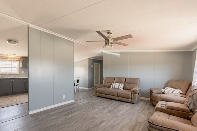 living room with ceiling fan, sink, crown molding, hardwood / wood-style floors, and a textured ceiling