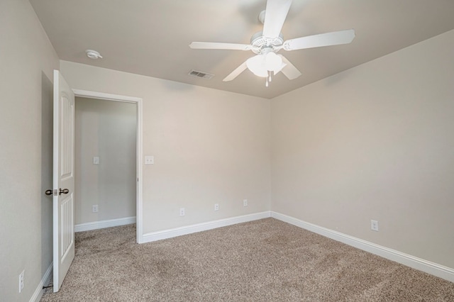 carpeted empty room with ceiling fan, visible vents, and baseboards