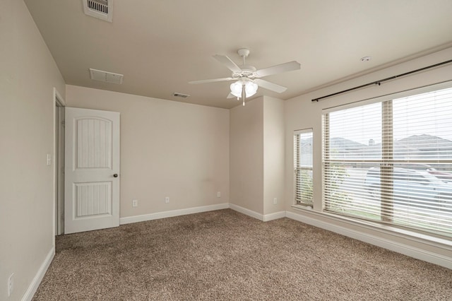 carpeted spare room with baseboards, visible vents, and a ceiling fan