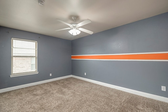 carpeted empty room featuring a ceiling fan and baseboards