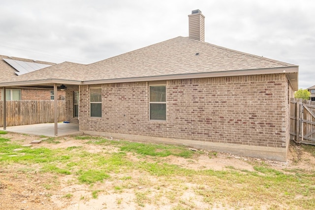 back of property featuring a shingled roof, a patio area, fence, and brick siding