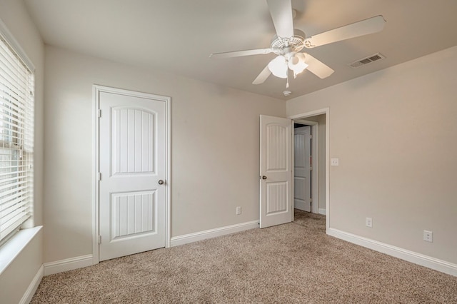 unfurnished bedroom featuring a ceiling fan, light colored carpet, visible vents, and baseboards