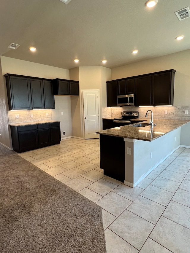 kitchen with sink, backsplash, kitchen peninsula, light carpet, and appliances with stainless steel finishes