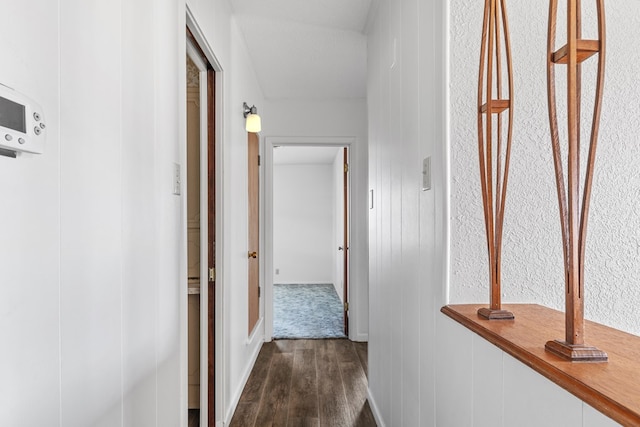 corridor with a textured ceiling and dark wood-type flooring