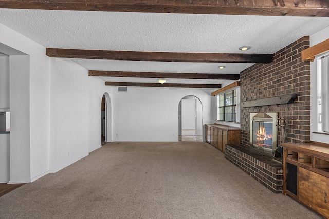 unfurnished living room featuring carpet, a textured ceiling, and a brick fireplace