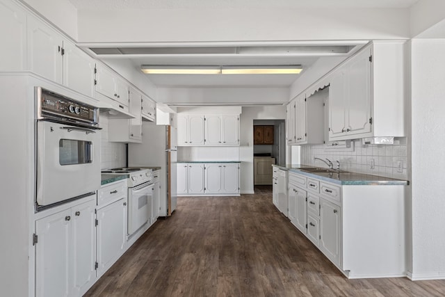 kitchen with white cabinetry, sink, dark wood-type flooring, backsplash, and white appliances