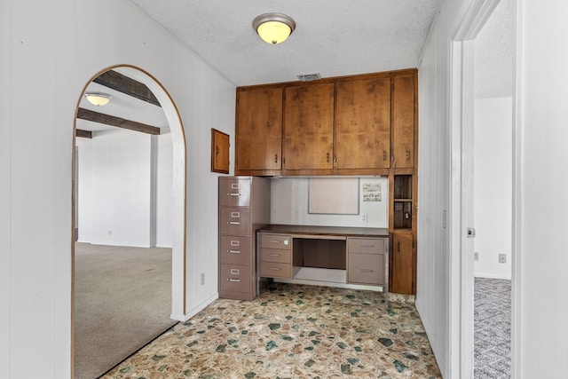 kitchen featuring light carpet, wood walls, and a textured ceiling