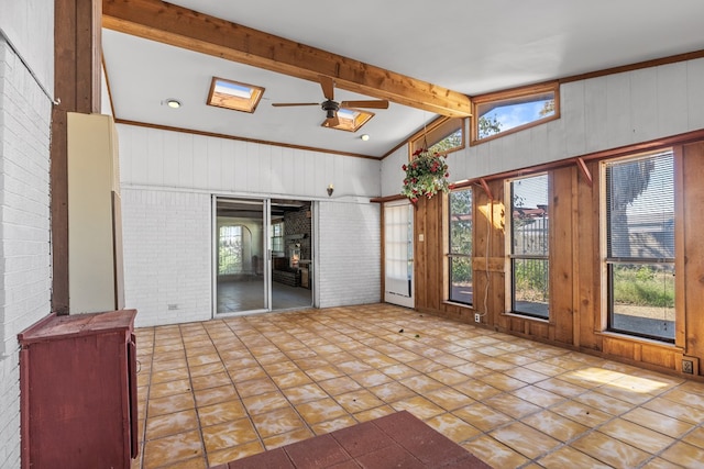 interior space featuring vaulted ceiling with beams, a healthy amount of sunlight, and brick wall