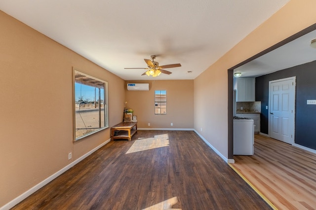 interior space with ceiling fan, an AC wall unit, and dark hardwood / wood-style flooring