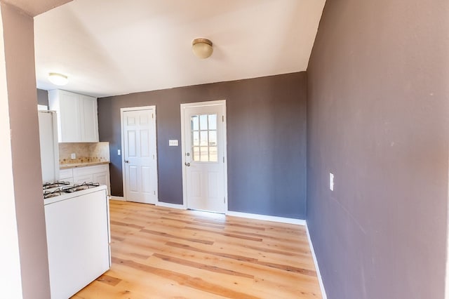 kitchen featuring white cabinetry, white gas range, backsplash, and light hardwood / wood-style flooring