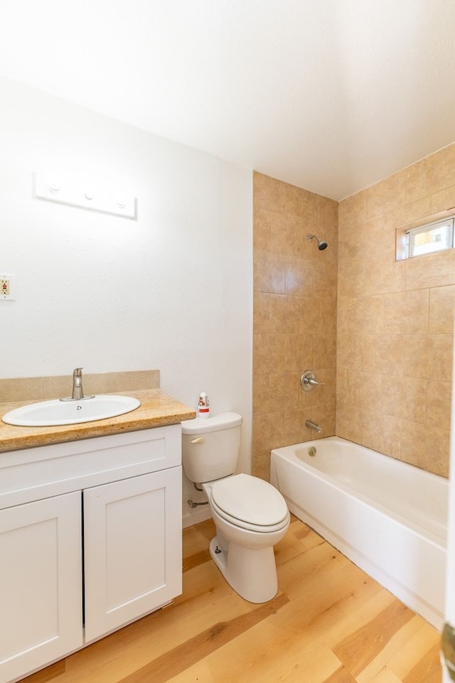 full bathroom featuring hardwood / wood-style flooring, tiled shower / bath, vanity, and toilet