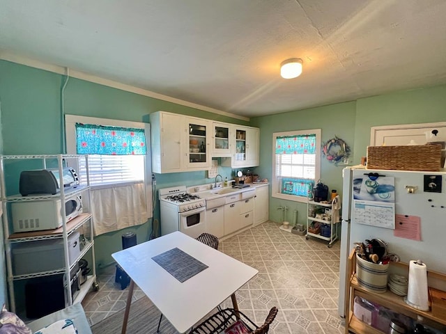 kitchen with white appliances, white cabinets, sink, and plenty of natural light