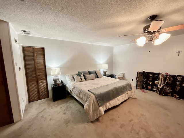 bedroom with carpet flooring, ceiling fan, a closet, and a textured ceiling