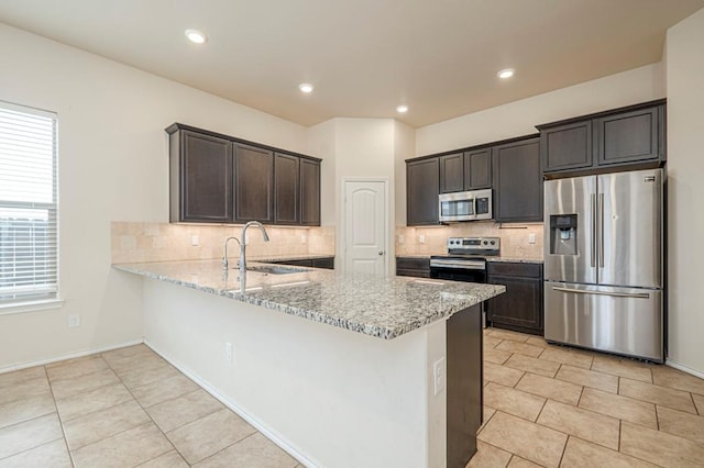 kitchen featuring sink, light tile patterned floors, dark brown cabinets, stainless steel appliances, and decorative backsplash