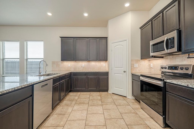 kitchen with sink, light stone counters, tasteful backsplash, light tile patterned floors, and stainless steel appliances