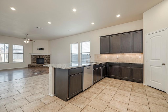 kitchen featuring a healthy amount of sunlight, dishwasher, kitchen peninsula, and light tile patterned floors