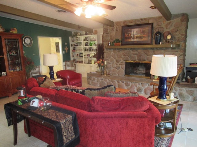 tiled living room with beam ceiling, a stone fireplace, and ceiling fan