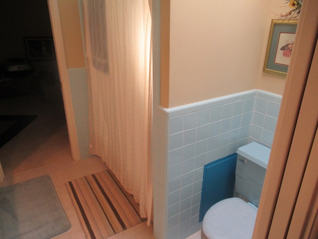 bathroom featuring tile patterned floors, toilet, and tile walls