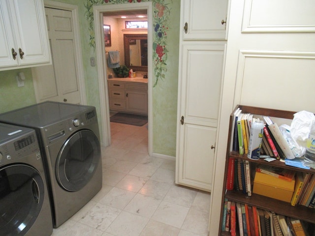 washroom featuring washing machine and clothes dryer, sink, and cabinets