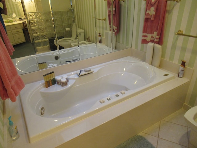 bathroom with tile patterned flooring, a tub to relax in, toilet, and a bidet