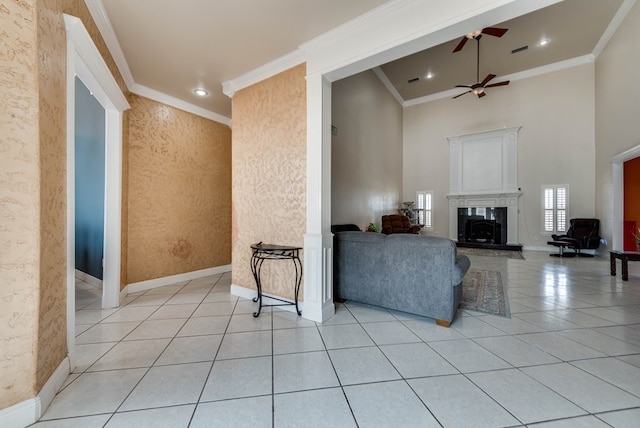 tiled living room with ceiling fan, a high ceiling, and ornamental molding