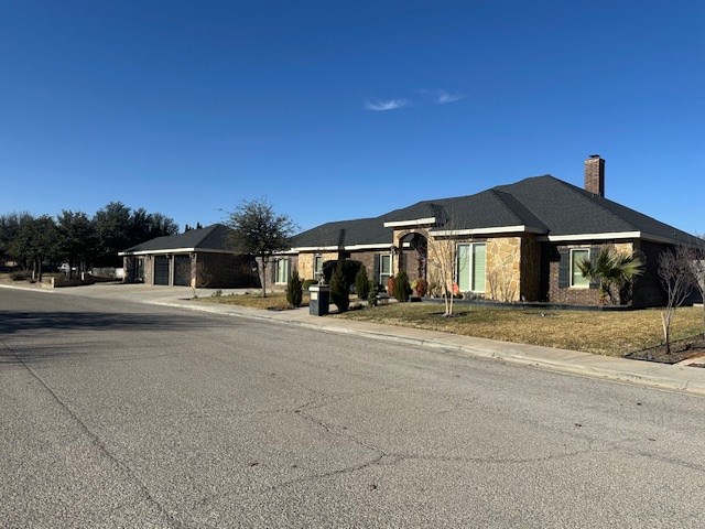 ranch-style house with a garage, driveway, and a chimney