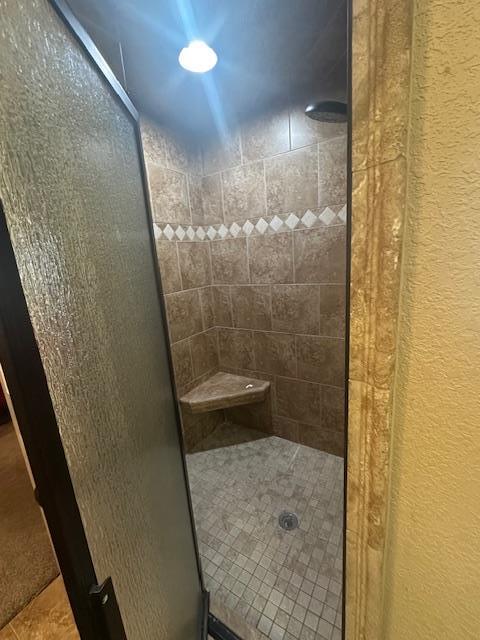 bathroom with tile patterned flooring, a shower stall, and a textured wall