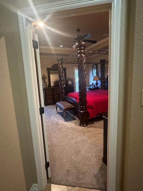 bedroom with ornamental molding, a ceiling fan, a textured wall, and carpet floors