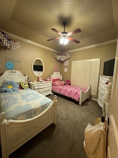 carpeted bedroom with ceiling fan, a raised ceiling, and ornamental molding