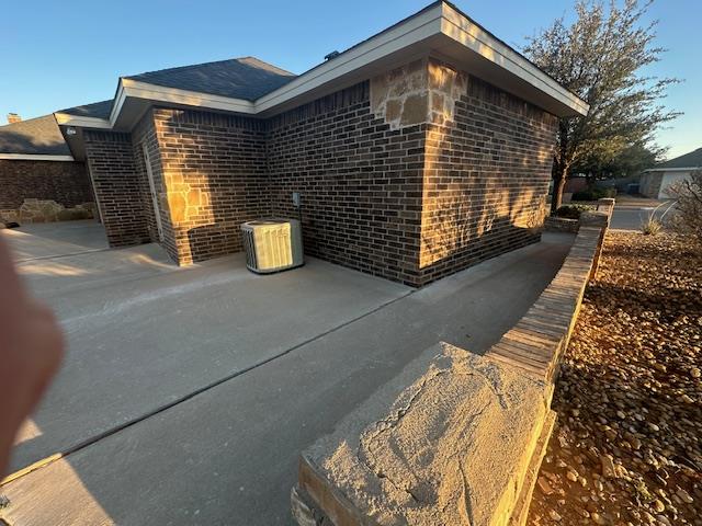 view of home's exterior with brick siding and a patio