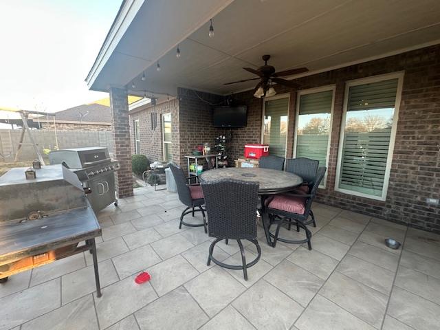 view of patio with grilling area, outdoor dining area, a ceiling fan, and fence