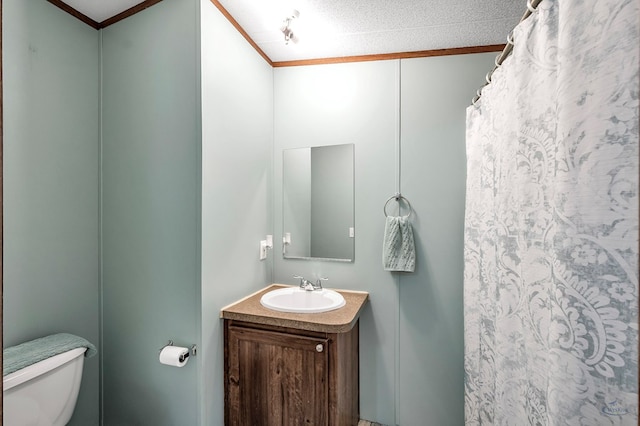 bathroom with a textured ceiling, vanity, toilet, and crown molding