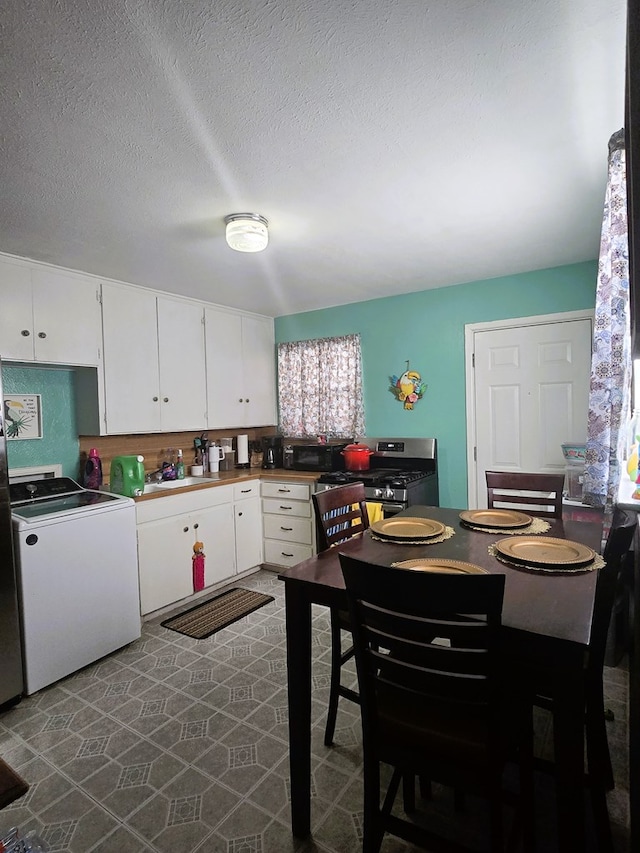 kitchen featuring washer / dryer, white cabinets, gas stove, a textured ceiling, and a sink