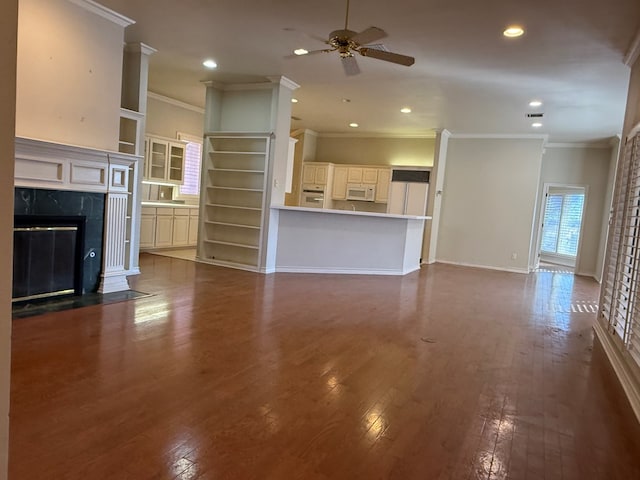 unfurnished living room featuring dark wood finished floors, recessed lighting, a high end fireplace, ceiling fan, and baseboards