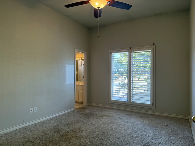 carpeted spare room with a ceiling fan and baseboards