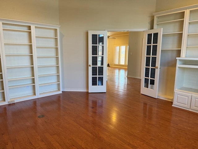 empty room featuring baseboards, wood finished floors, and french doors