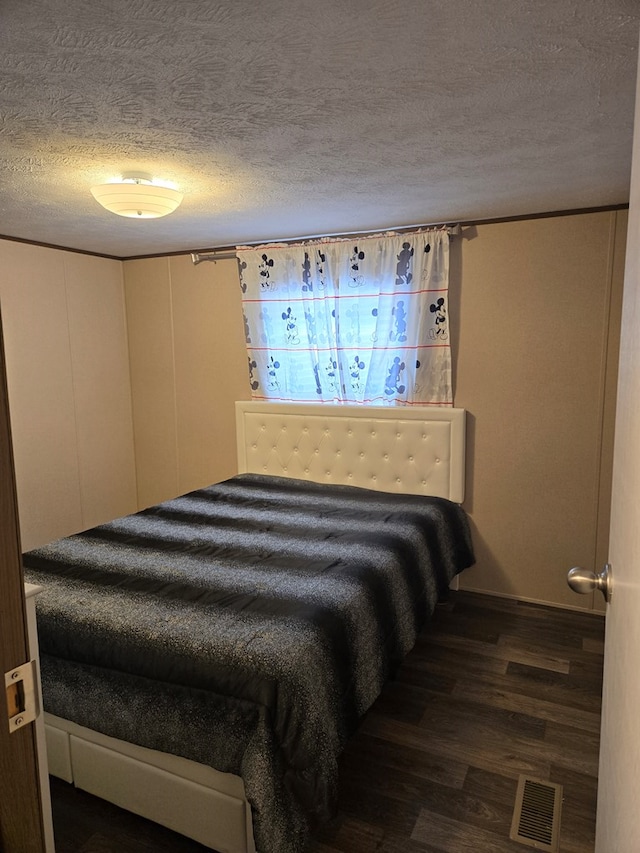 bedroom with dark wood-type flooring and a textured ceiling